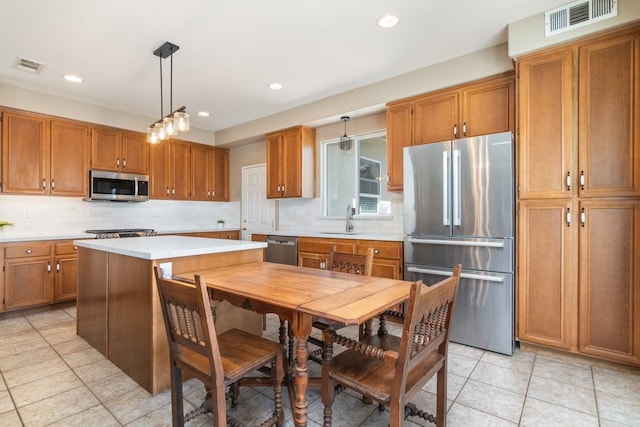 32133 Kale Ln, Winchester, CA 92596 - kitchen featuring stainless steel appliances, a sink, brown cabinetry, light countertops, and tasteful backsplash