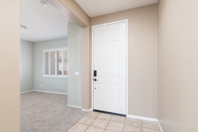 entryway with light tile patterned floors, baseboards, light colored carpet, and visible vents