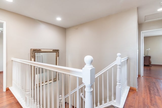 corridor featuring wood finished floors, baseboards, an upstairs landing, and recessed lighting