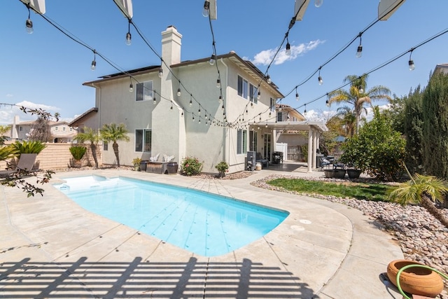 rear view of house featuring a fenced in pool, a patio, stucco siding, a chimney, and fence