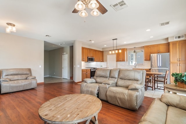 living area featuring visible vents, a ceiling fan, and wood finished floors