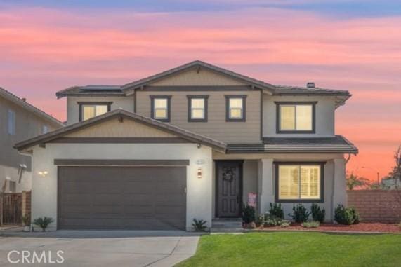 traditional-style house with fence, stucco siding, a lawn, and concrete driveway