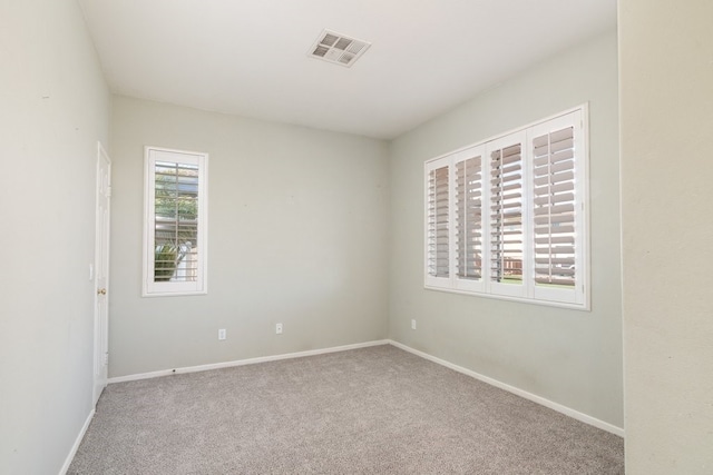 empty room featuring carpet floors, baseboards, and visible vents