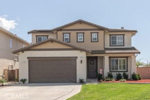 traditional home with stucco siding, fence, a front lawn, an attached garage, and concrete driveway