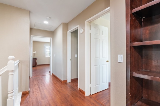 corridor featuring baseboards, an upstairs landing, attic access, and wood finished floors