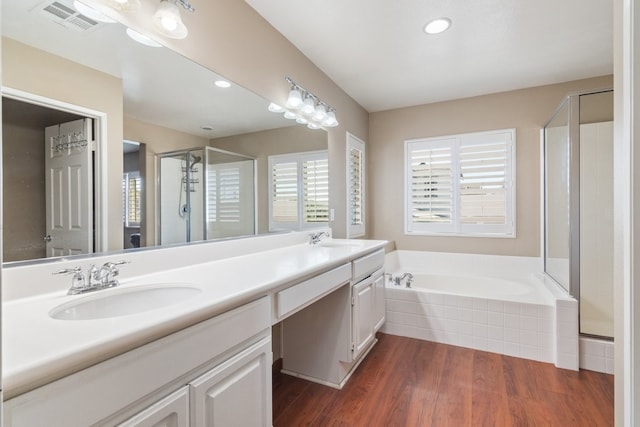 bathroom with a shower stall, a garden tub, visible vents, and a sink