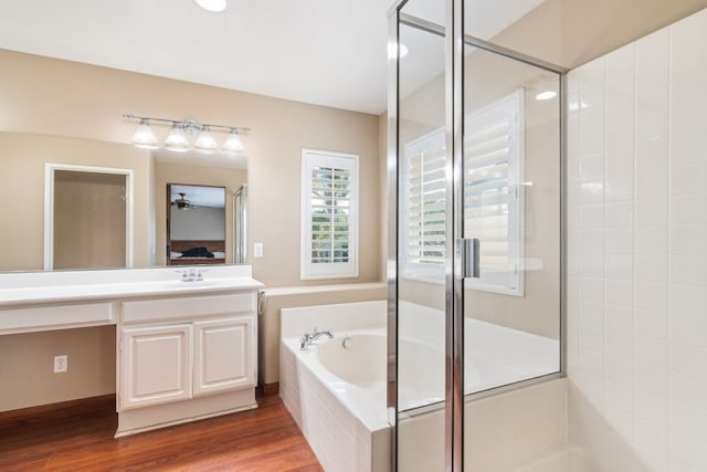 bathroom featuring a shower stall, vanity, a bath, and wood finished floors