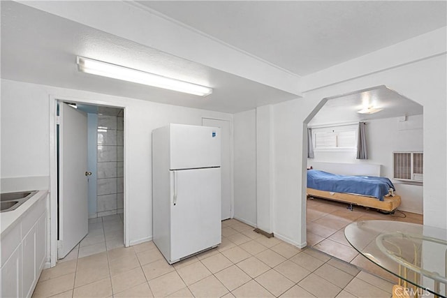kitchen with freestanding refrigerator, a sink, white cabinetry, and light tile patterned floors