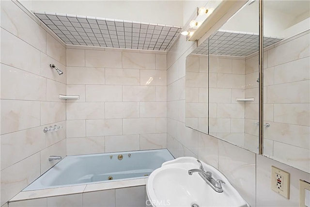 bathroom with tiled shower / bath combo and a sink