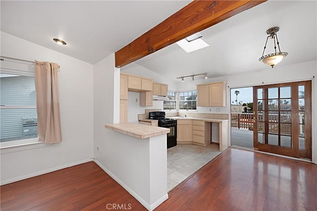 kitchen with black range with gas cooktop, a peninsula, under cabinet range hood, and light wood finished floors