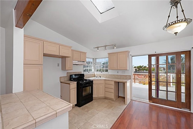 kitchen featuring under cabinet range hood, lofted ceiling with skylight, black range with gas cooktop, and cream cabinets