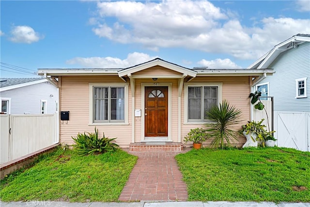 bungalow-style house featuring a front lawn and fence