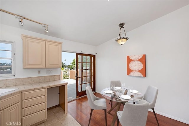 dining room with rail lighting, light wood finished floors, and baseboards