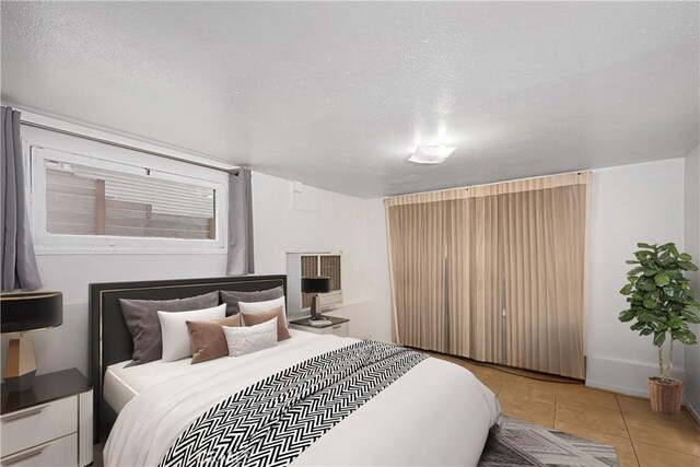 tiled bedroom with baseboards and a textured ceiling