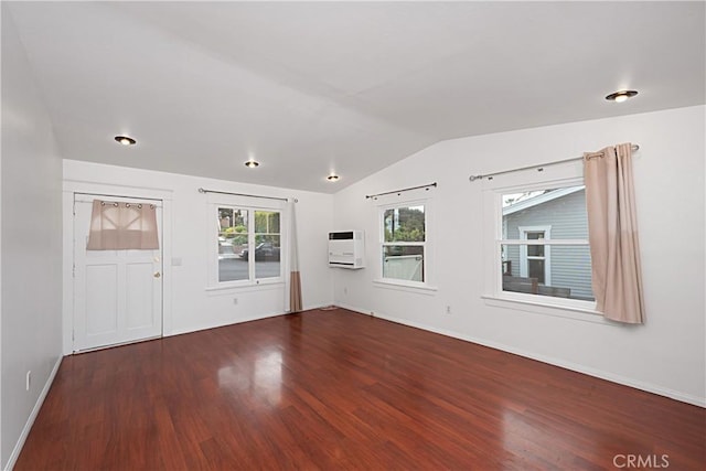 spare room with lofted ceiling, baseboards, heating unit, and wood finished floors