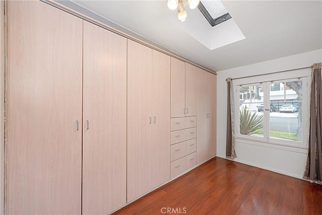unfurnished bedroom featuring a skylight, wood finished floors, and a closet