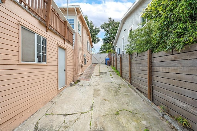 view of side of home featuring a gate, concrete driveway, a patio, and fence