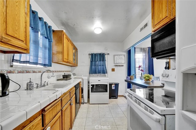 2807 W 129th, Gardena, CA 90248 - kitchen with tile countertops, light tile patterned floors, black appliances, a sink, and washer / dryer