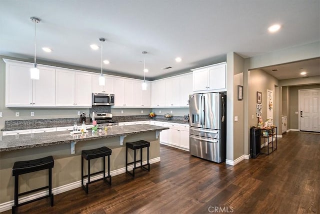 17985 Crabapple Ct, San Bernardino, CA 92407 - kitchen featuring dark wood-style flooring, a kitchen breakfast bar, white cabinetry, dark stone counters, and appliances with stainless steel finishes
