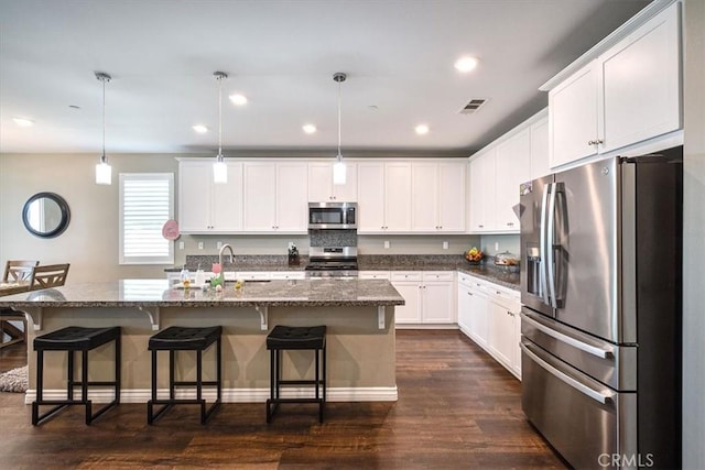 17985 Crabapple Ct, San Bernardino, CA 92407 - kitchen with dark wood-style floors, white cabinets, visible vents, a kitchen bar, and stainless steel appliances