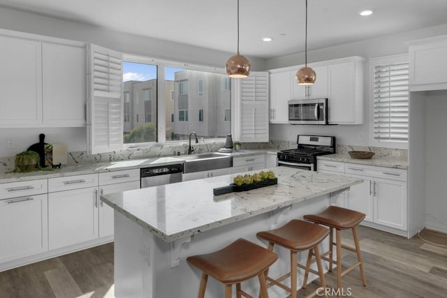 8000 7th St, Downey, CA 90241 - kitchen with a center island, light wood-style flooring, a sink, stainless steel appliances, and white cabinetry