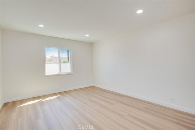 spare room with light wood-type flooring, baseboards, and recessed lighting