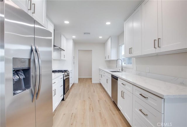kitchen with white cabinets, a sink, light wood-type flooring, recessed lighting, and stainless steel appliances