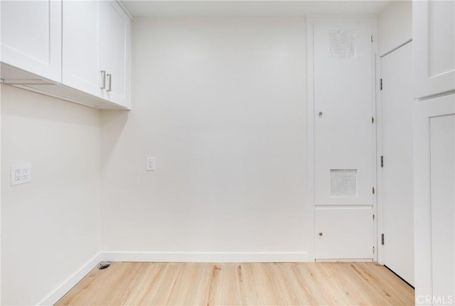 washroom featuring cabinet space, light wood-style flooring, and baseboards