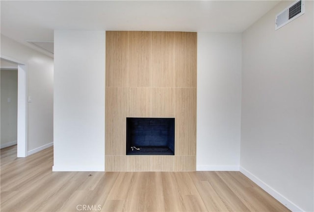 interior details with visible vents, baseboards, wood finished floors, and a fireplace