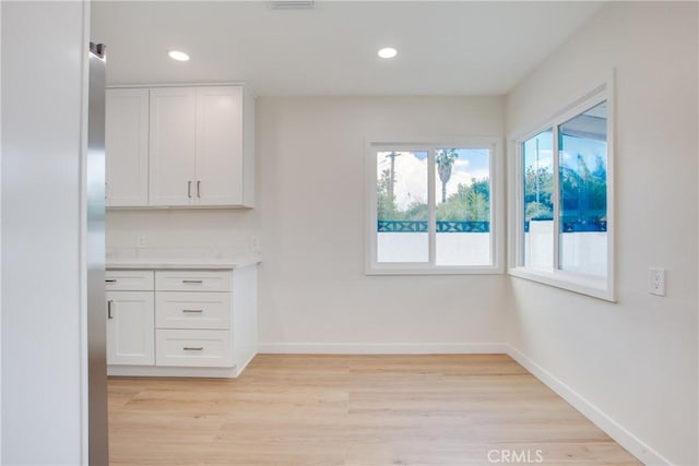 unfurnished dining area featuring baseboards, light wood finished floors, and recessed lighting