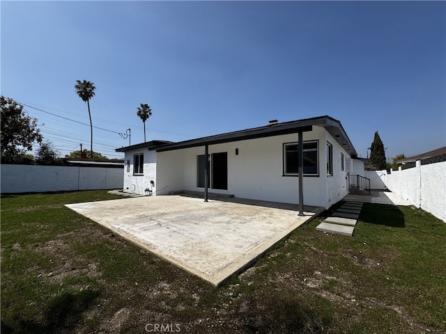 rear view of house with a patio, a fenced backyard, stucco siding, and a lawn