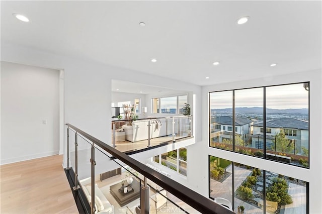 corridor featuring recessed lighting, an upstairs landing, wood finished floors, and a healthy amount of sunlight