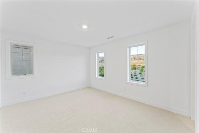 spare room featuring visible vents, baseboards, recessed lighting, and light carpet