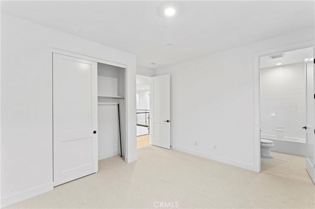 unfurnished bedroom with ensuite bathroom, carpet, a closet, visible vents, and baseboards