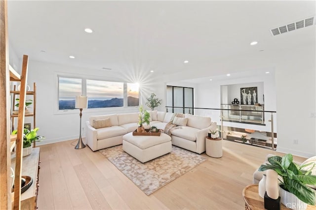 living room with recessed lighting, visible vents, baseboards, and wood finished floors