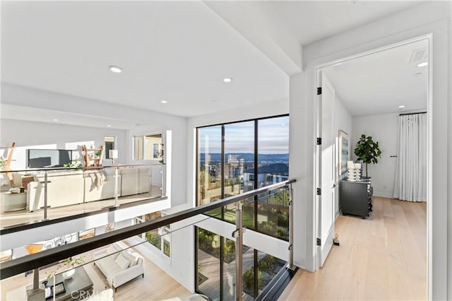 hallway featuring baseboards, recessed lighting, and light wood-style floors