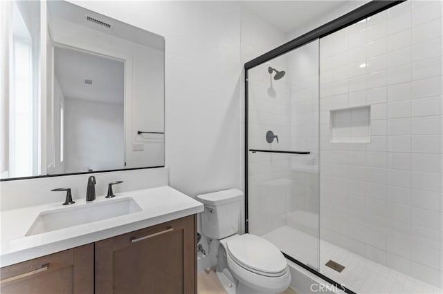 bathroom featuring a shower stall, vanity, visible vents, and toilet