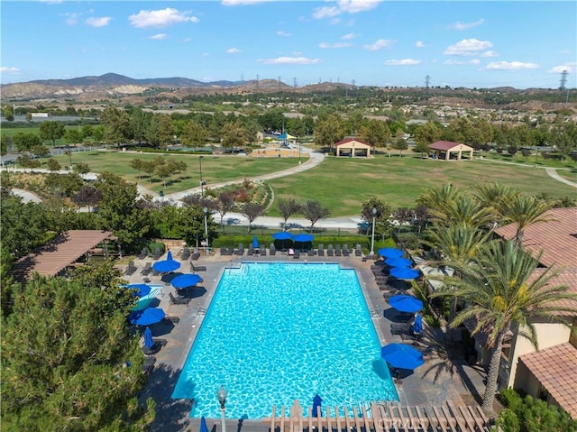 pool featuring a mountain view, fence, a patio area, and a lawn