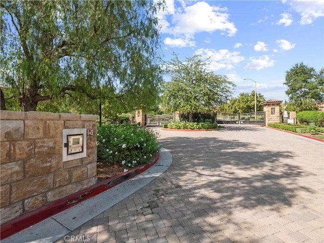 exterior space with street lighting, a gated entry, curbs, and a gate