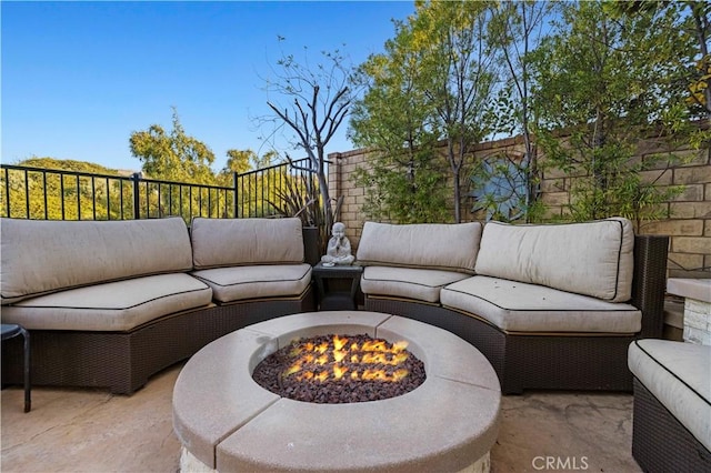 view of patio with an outdoor living space with a fire pit and fence