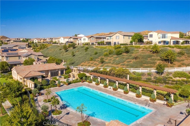 community pool featuring a patio area, fence, and a residential view