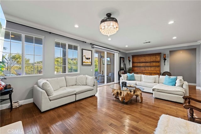 living area with a chandelier, hardwood / wood-style floors, baseboards, and ornamental molding