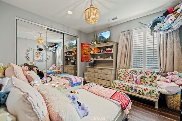 bedroom featuring visible vents, multiple windows, a notable chandelier, and wood finished floors