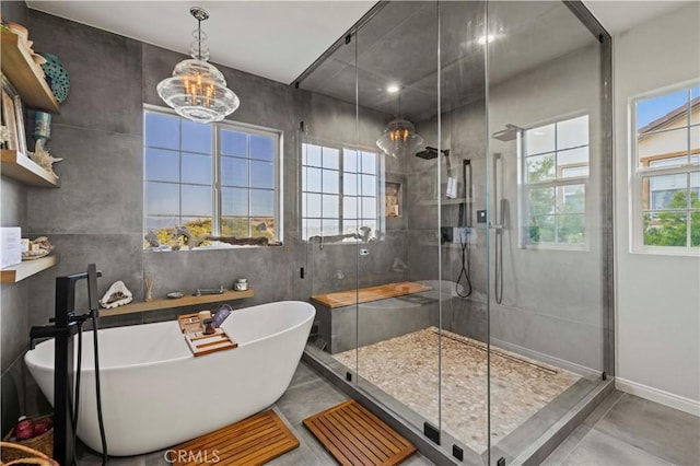 full bath featuring an inviting chandelier, a shower stall, a freestanding tub, concrete floors, and baseboards