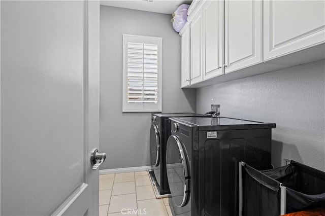 laundry area featuring separate washer and dryer, light tile patterned floors, baseboards, and cabinet space