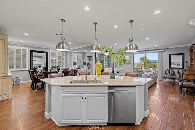 kitchen featuring dishwasher, a sink, open floor plan, ornamental molding, and an island with sink
