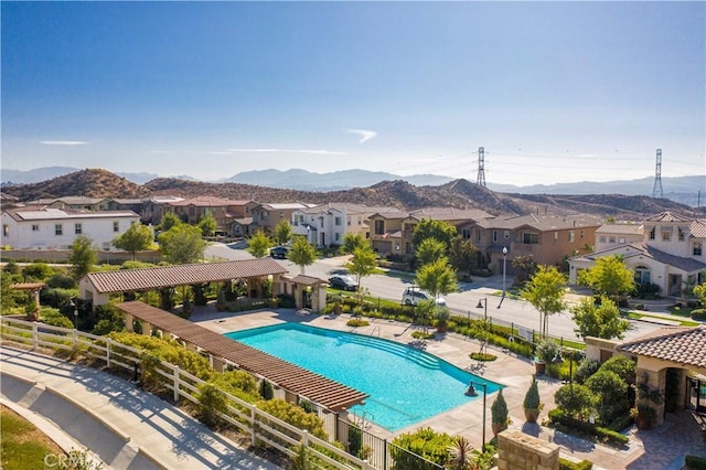 pool with a mountain view, fence, a residential view, and a patio area