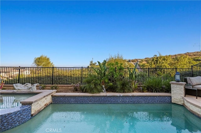 view of pool with a fenced backyard and a pool with connected hot tub