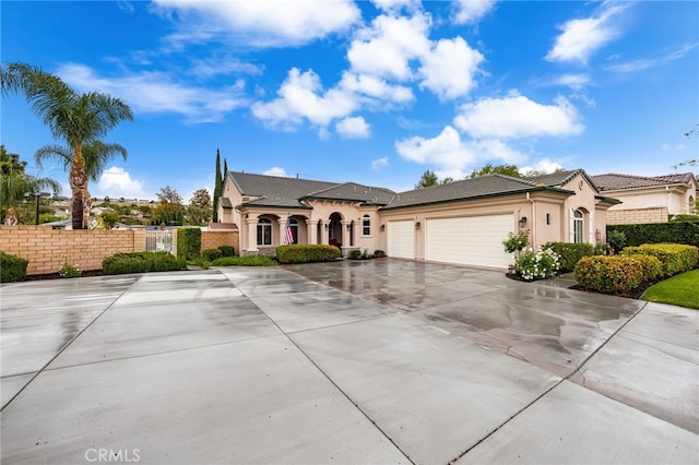 view of front facade featuring stucco siding, fence, concrete driveway, and an attached garage