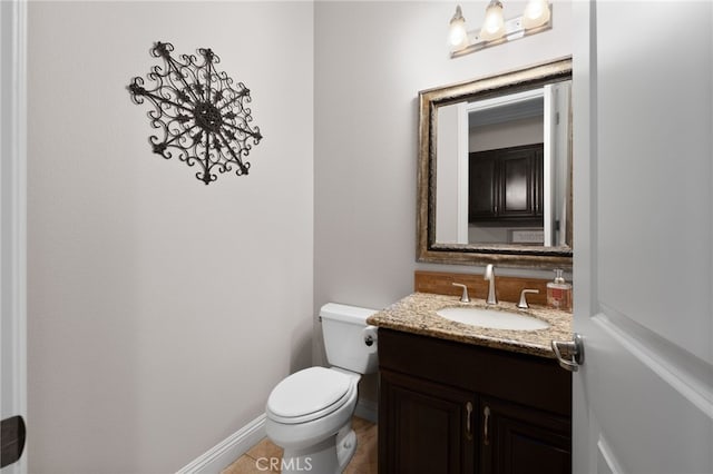 half bath featuring tile patterned floors, toilet, vanity, and baseboards